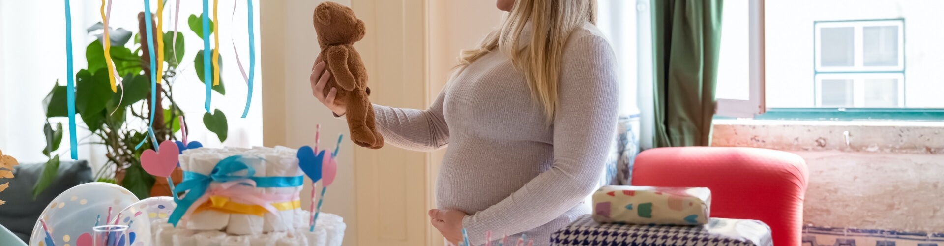 Pregnant Woman in Nursery Holding Teddy Bear